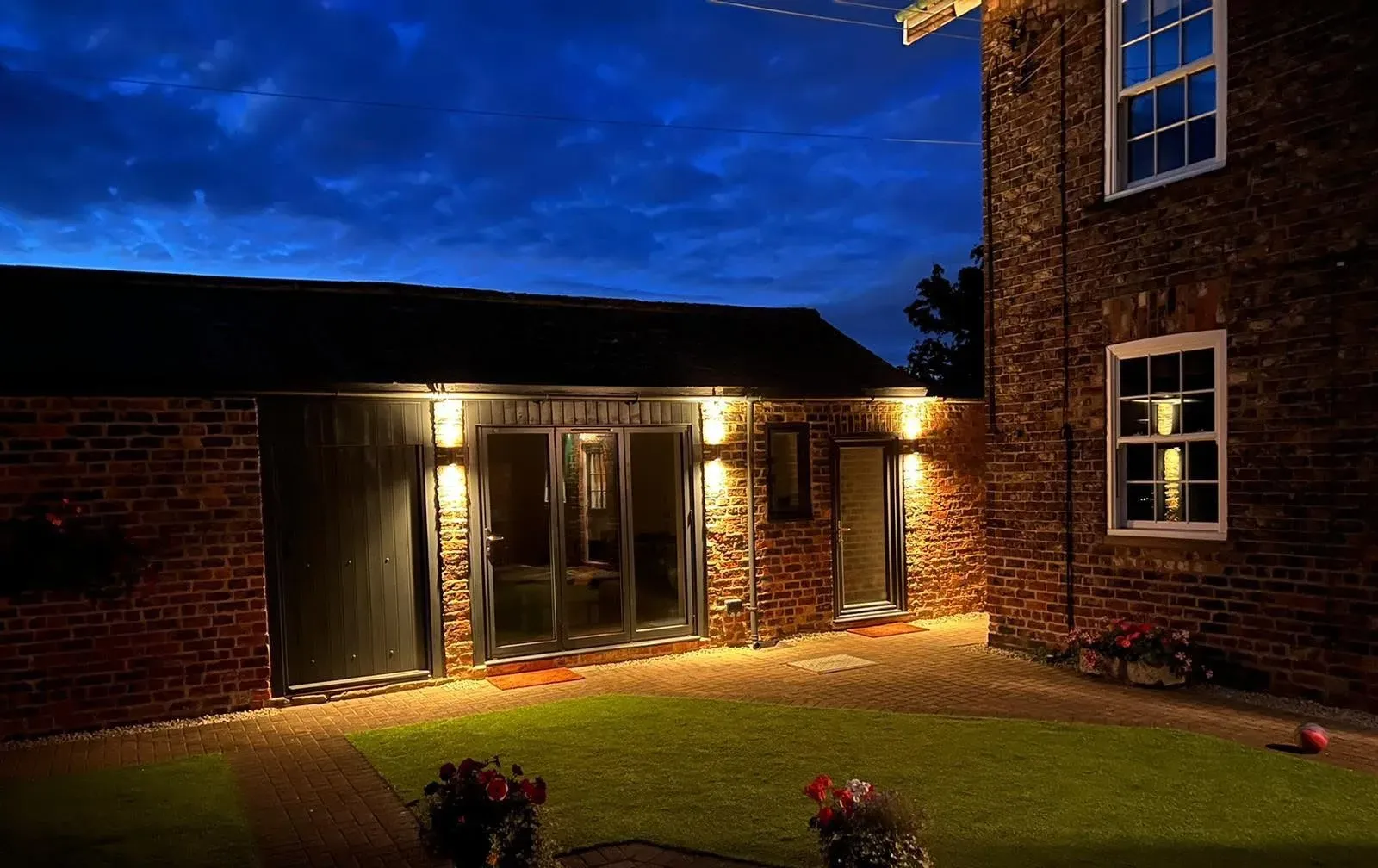 Converted outbuilding lit at dusk, built by RGS Joinery and Building